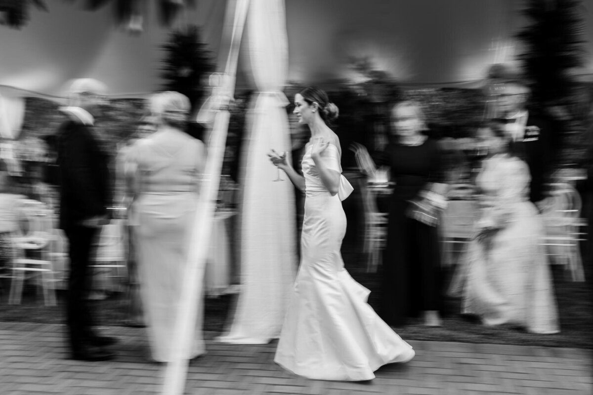 Bride walking through blurred crowd at a Charleston wedding venue – elegant motion photo in black and white.