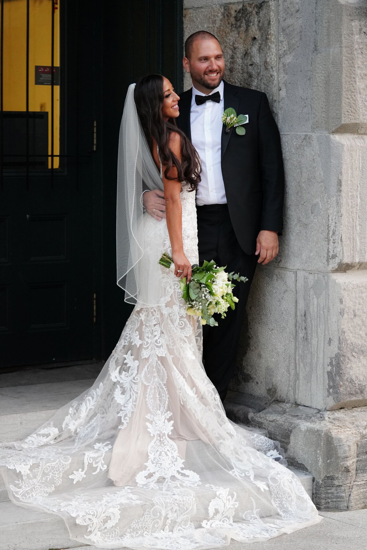 The bride and groom strike a stylish pose against a chic urban backdrop. The city's modern architecture and vibrant atmosphere complement their elegant wedding attire, creating a dynamic and sophisticated portrait of their special day.