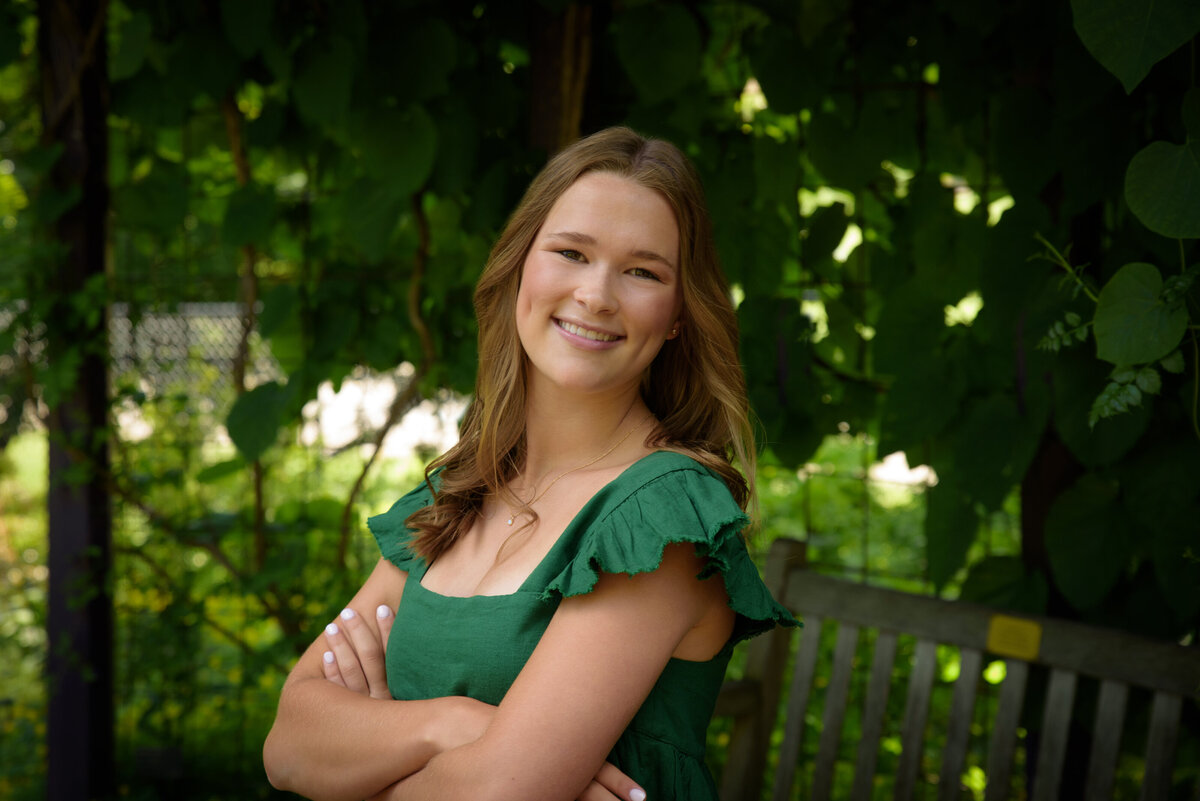 Luxemburg Casco High School senior girl wearing short kelly green dress standing surrounded by greenery  at the Green Bay Botanical Gardens in Green Bay, Wisconsin