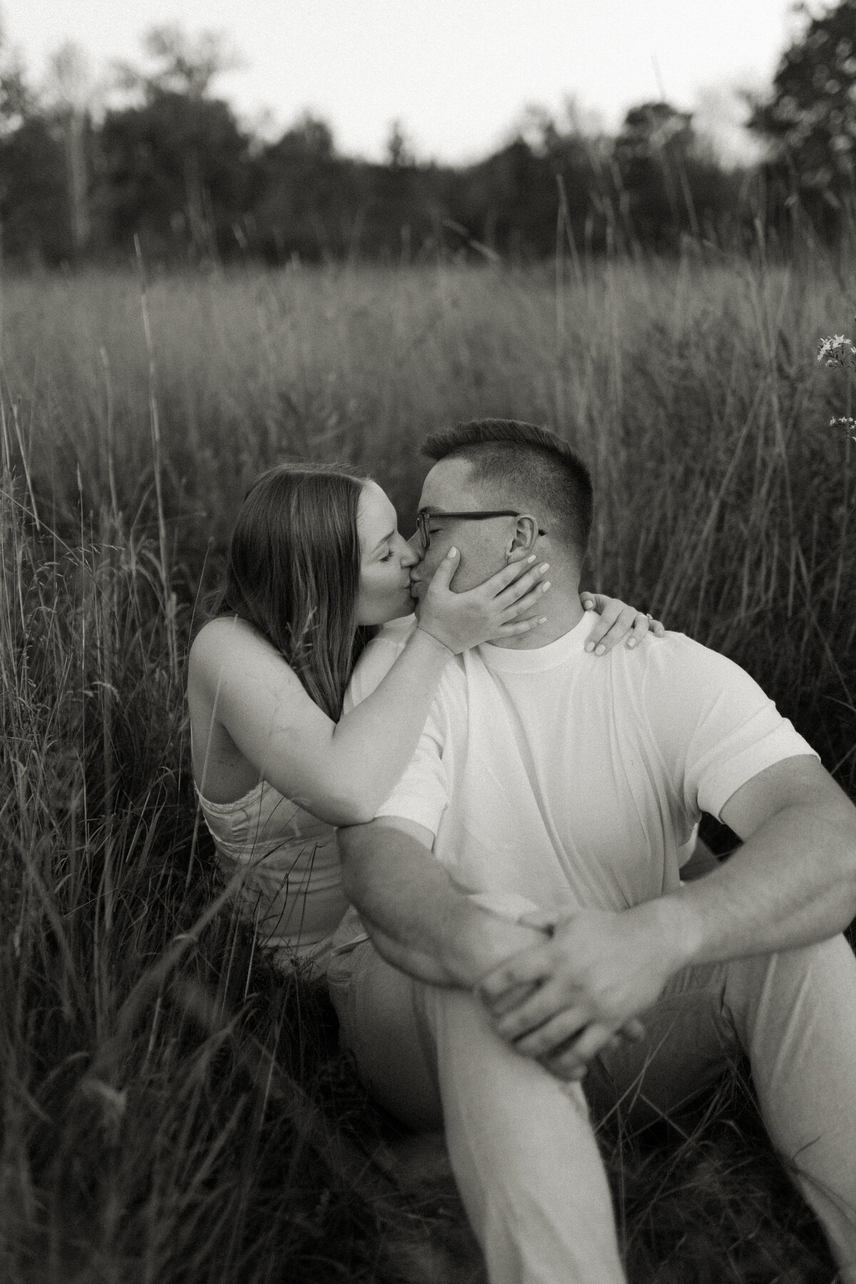 Coastal couple cozies up among beach grass at Minnesota Point during a Duluth engagement session photographed by Emmie Verdell Photo.