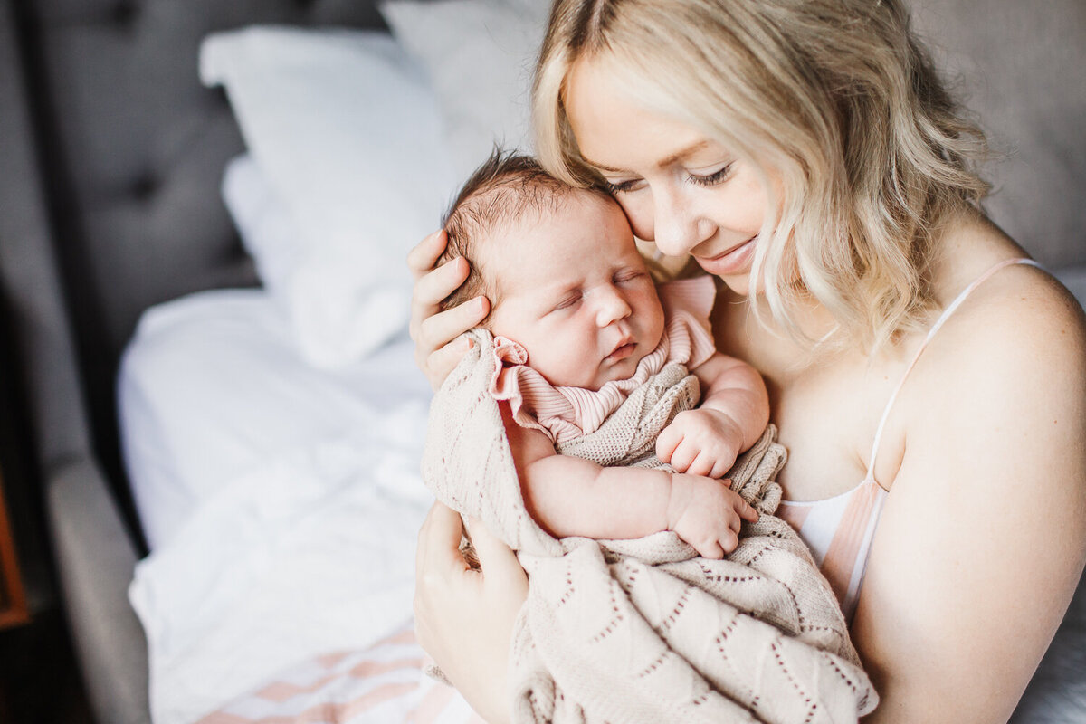 beautiful mom snuggling her new baby girl during newborn session