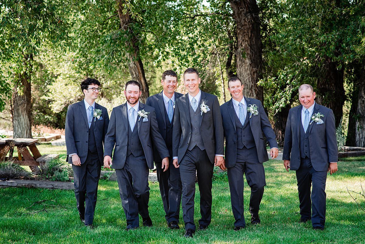 Groom with his groomsmen strolling through shaded area at Headwaters Ranch