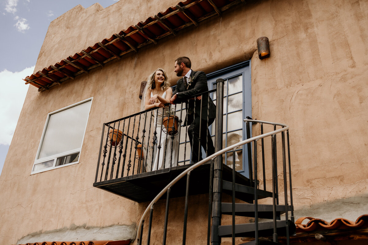 bride and groom standing on a balcony together on a southwestern adobe home
