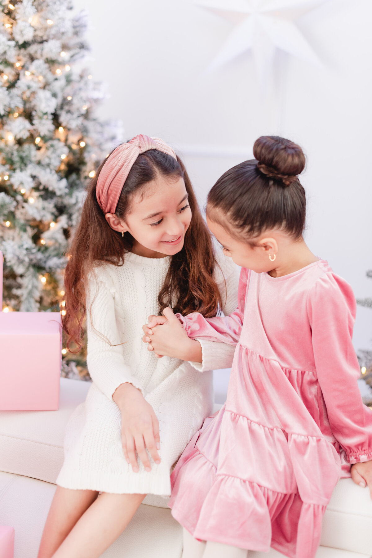 sisters wearing pink christmas outfits with pink christmas presents