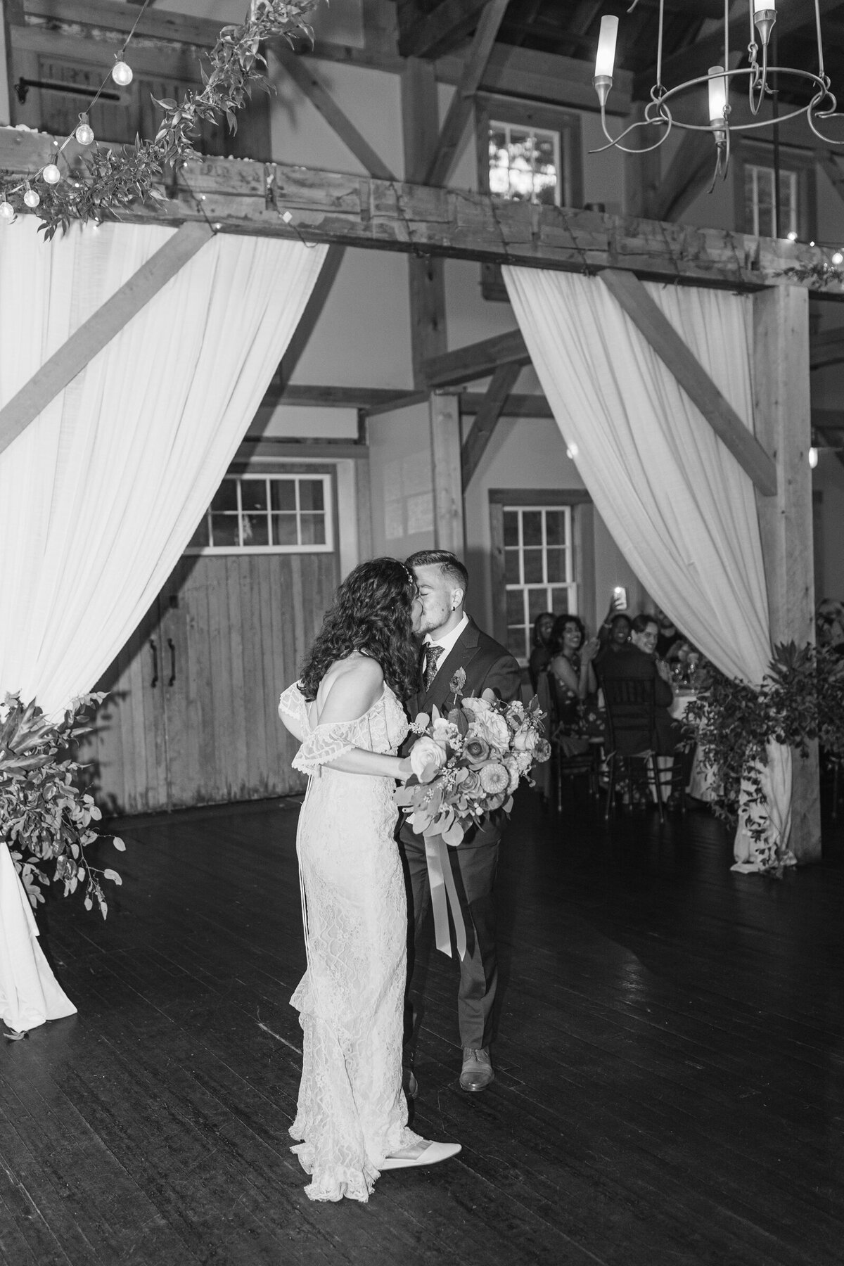 The bride and groom kiss at their wedding reception with a hard flash. 