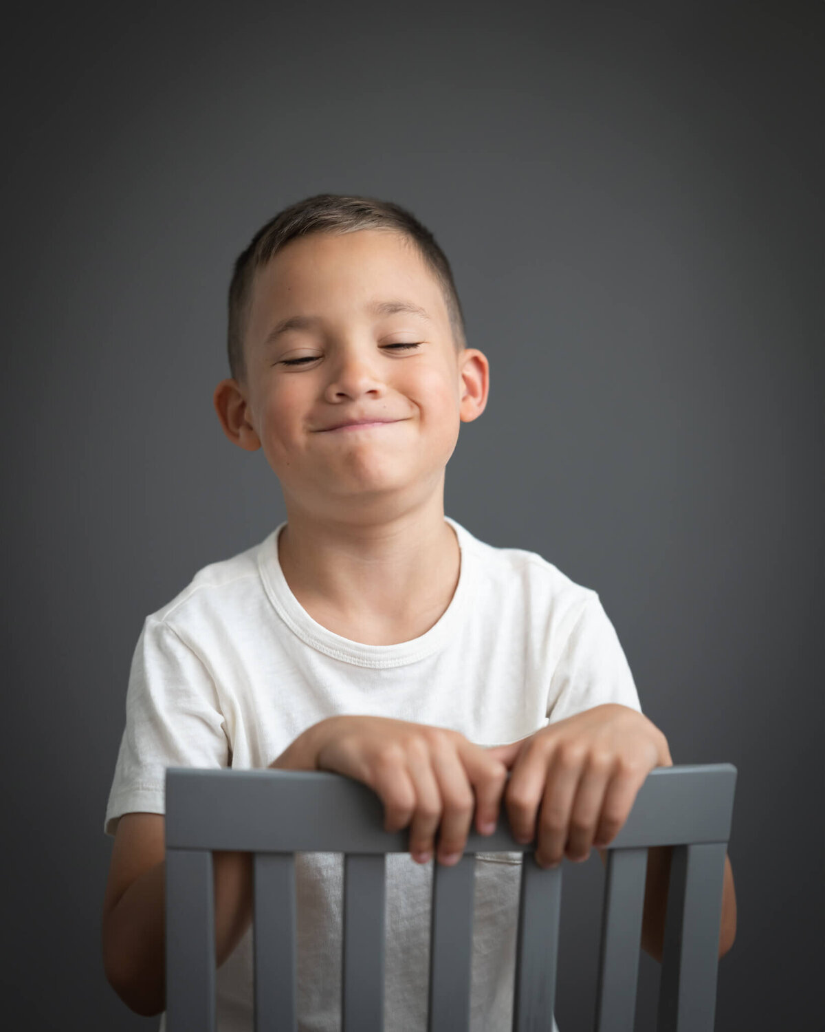 portrait of boy laughing with puffed cheeks in studio