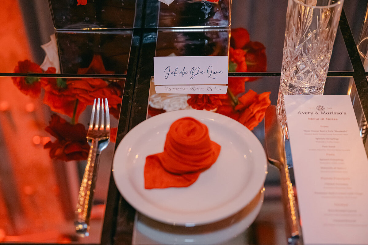 Custom name card and rose napkin atop clean mirrored place setting at luxury wedding in Texas