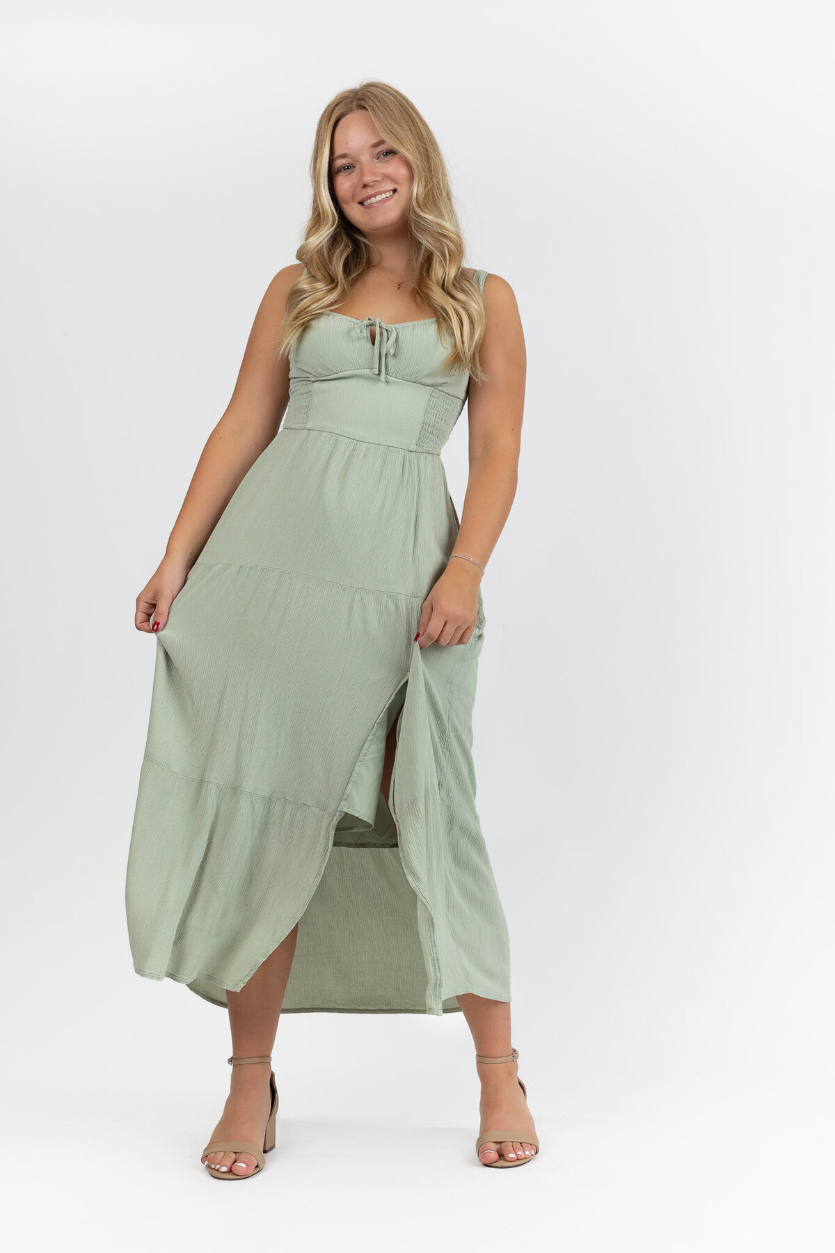 A senior girl grabbing green dress and moving back and forth on a white back drop in Lawrence, KS