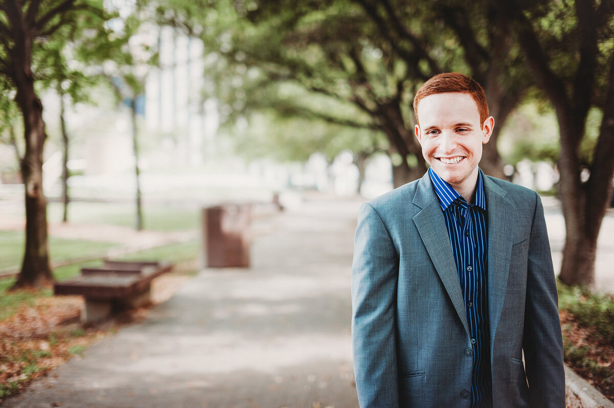 Man smiling during an outdoor portrait session on a shaded, tree-lined walkway in Downtown Orlando.