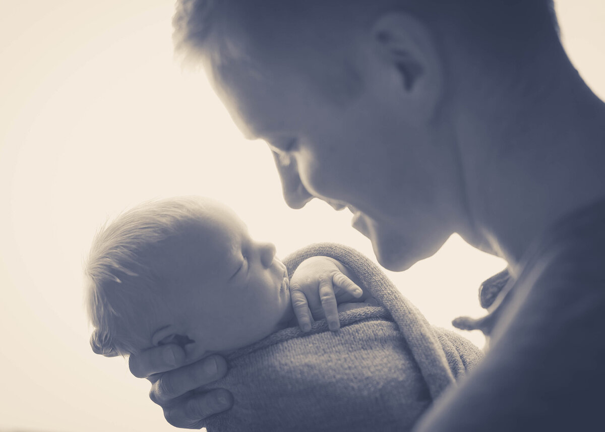 Dad holds his newborn baby in the window
