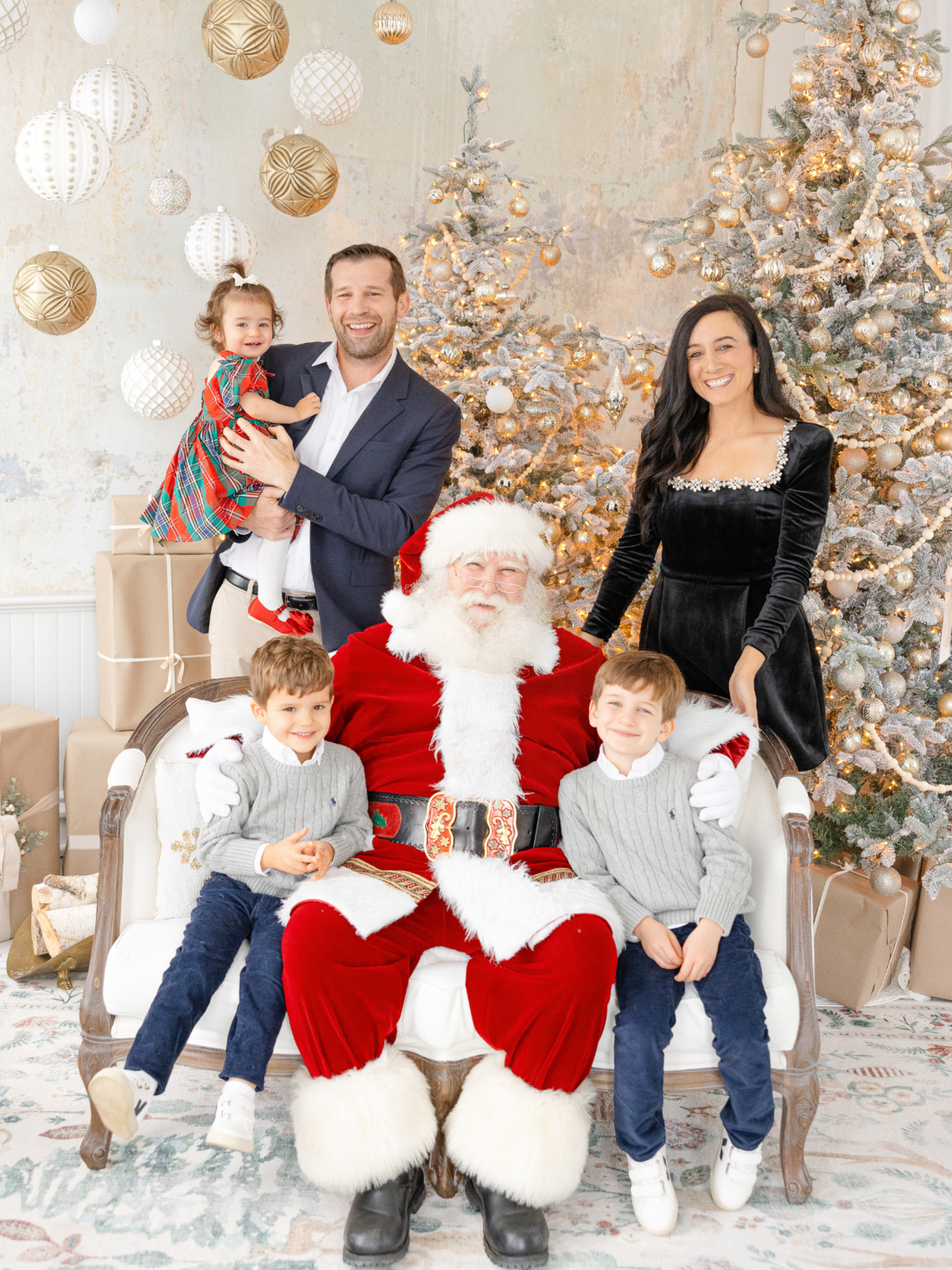 family of 5 wearing festive holiday clothing smiles for family photo with santa claus
