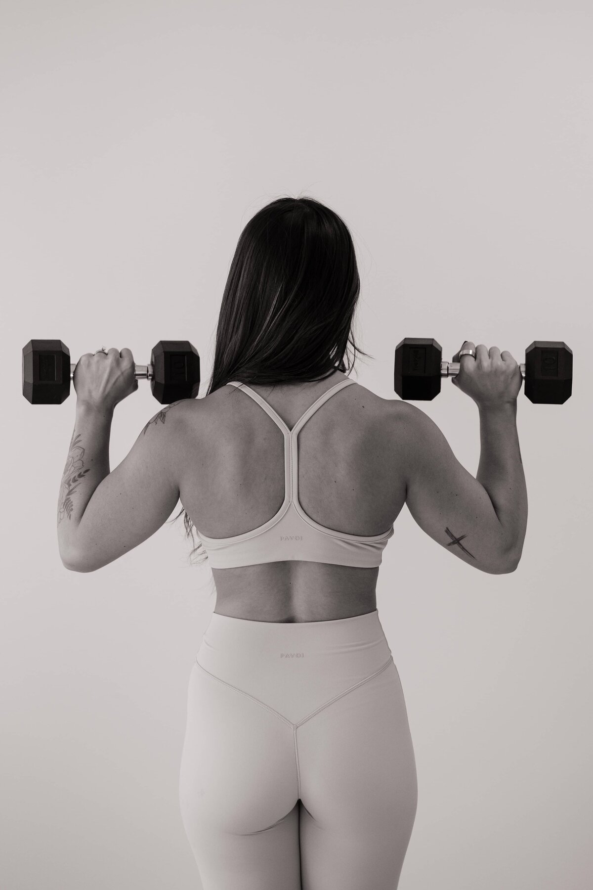 A black and white photo of a health coach holding weights. 