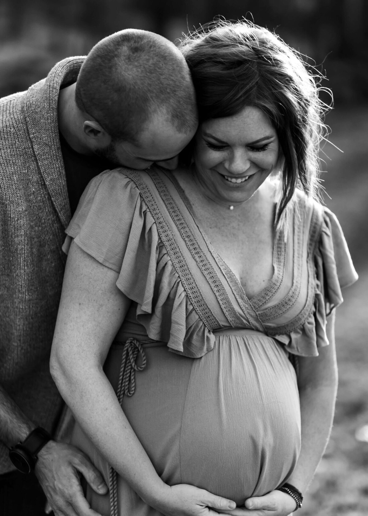 This black and white photo features a pregnant woman embracing her husband. Shot by a Pittsburgh maternity photographer.