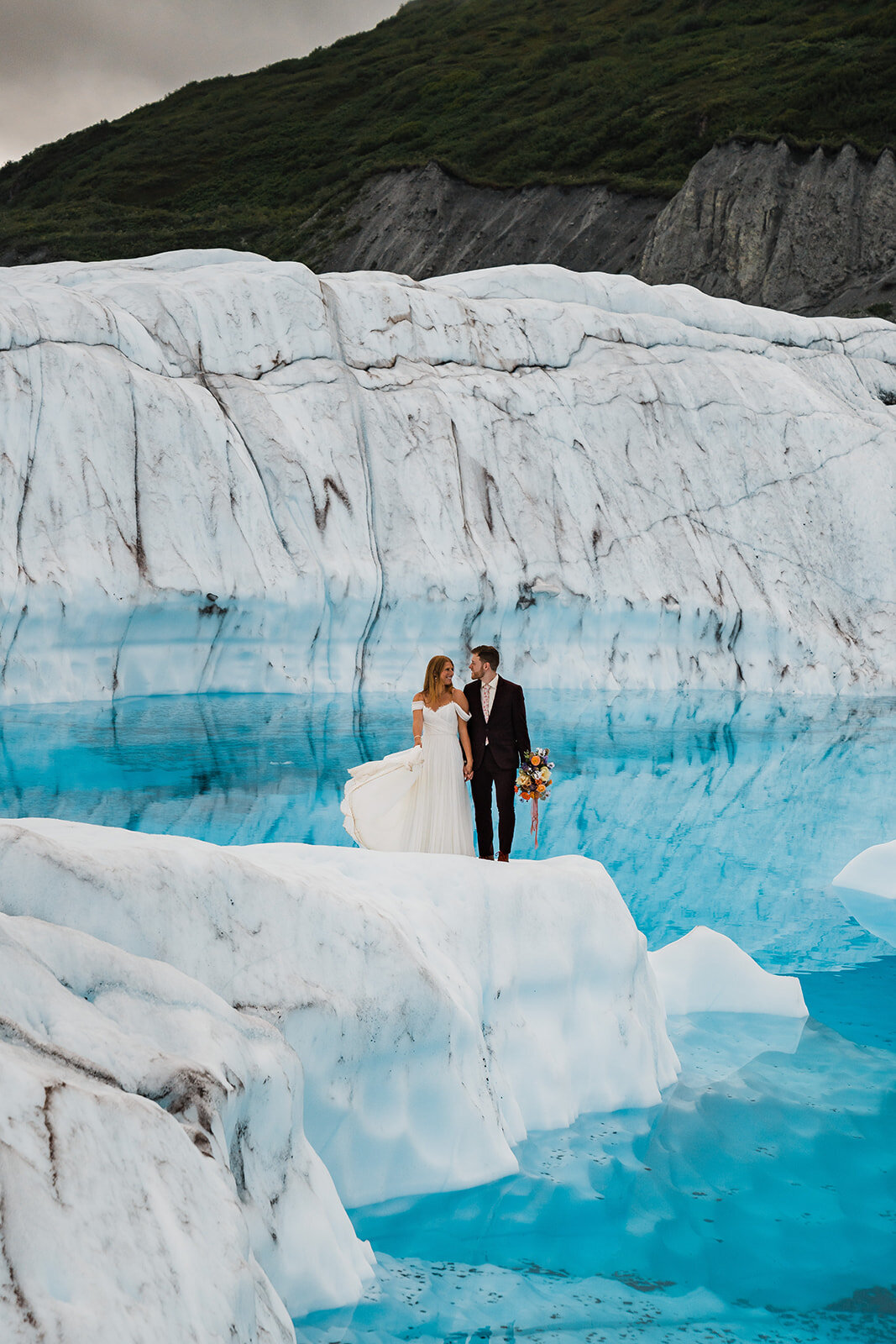 Bride & groom standing on glacier during adventurous helicopter elopement in Alaska!