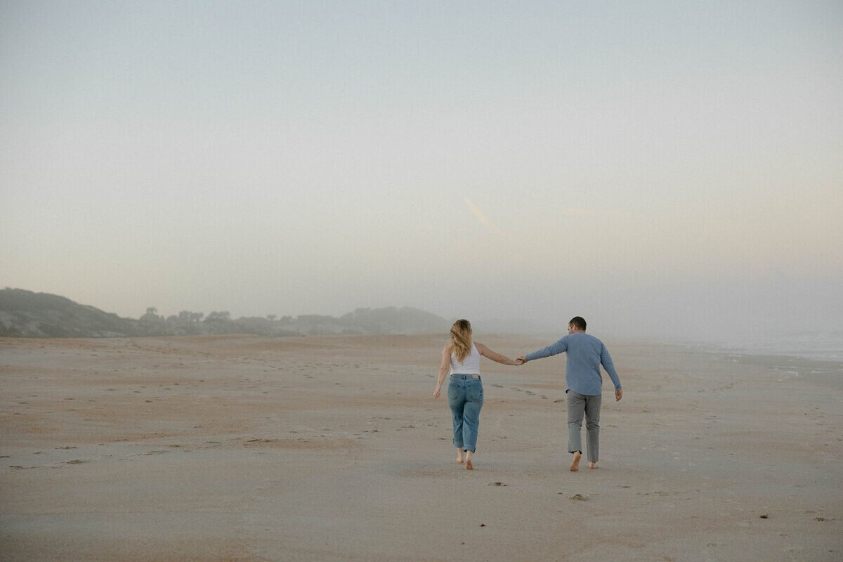 Couple running on beach taken by one of the best engagement photographers in orlando fl, Marissa Nicole