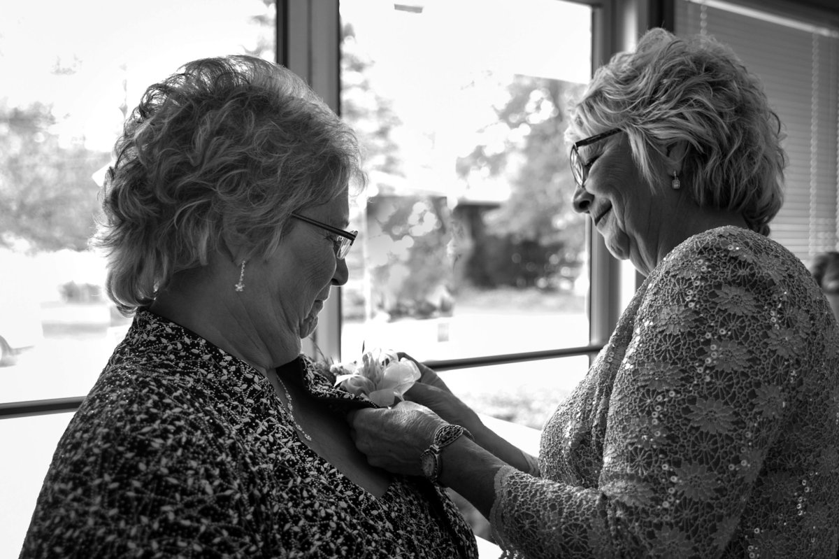 both mothers help each other with corsages