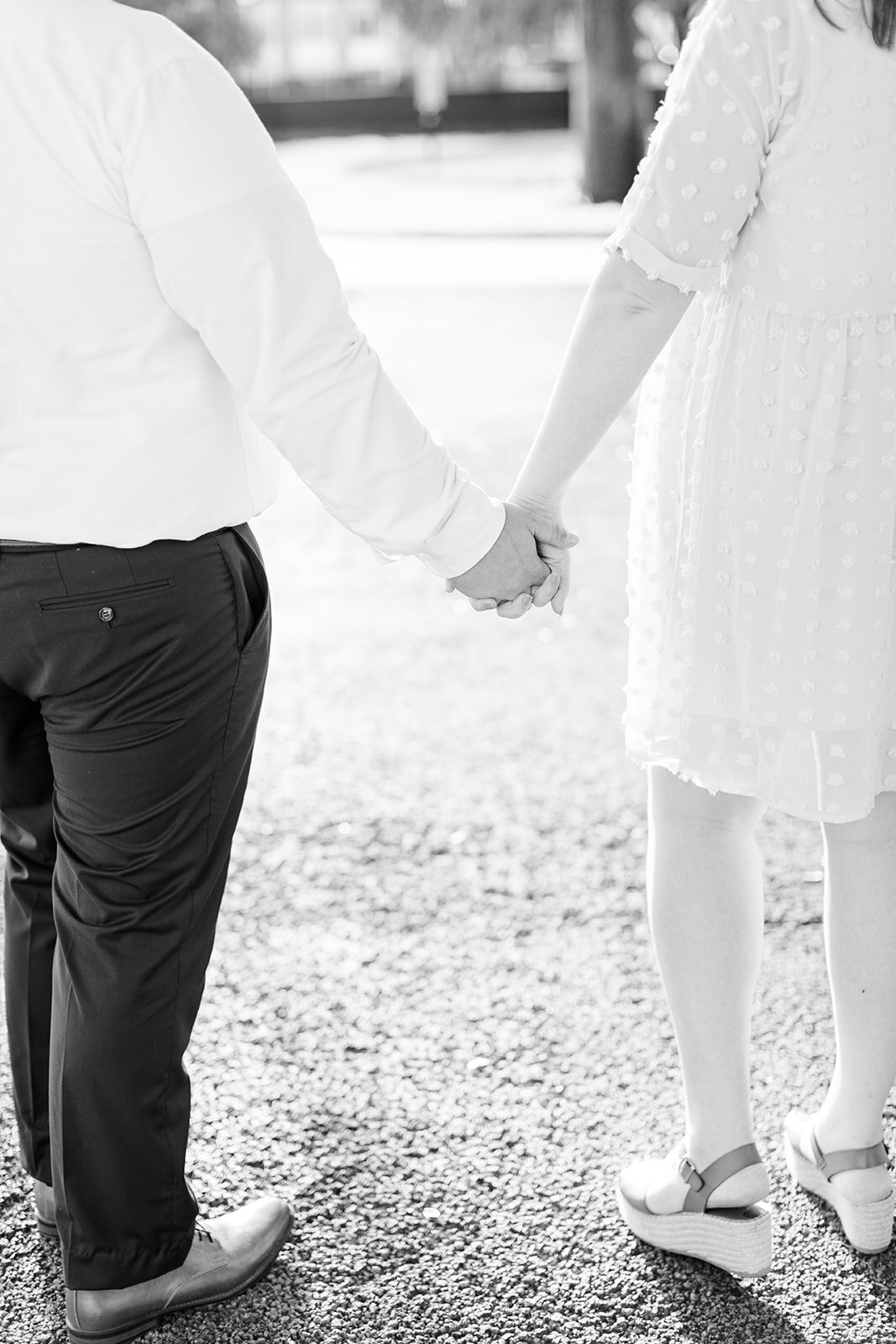 Engagement photo of couple holding hands in black and white