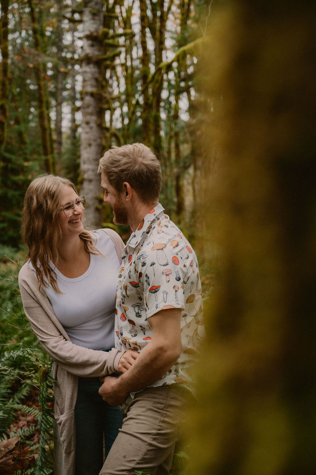 Couple smiling at each other behind tree