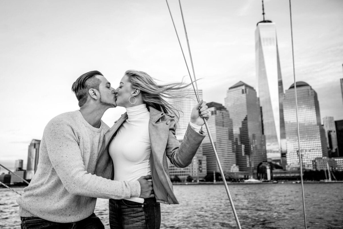 Man and woman kissing on a boat with New York City in the background