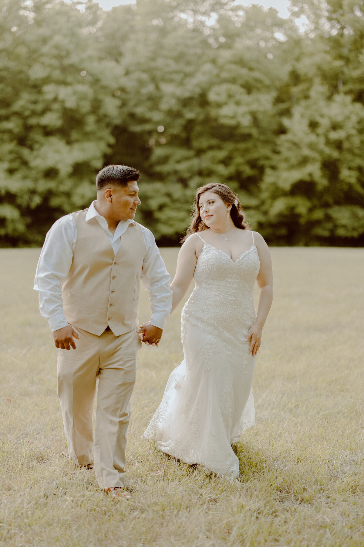 couple holding hands in field with bride and groom