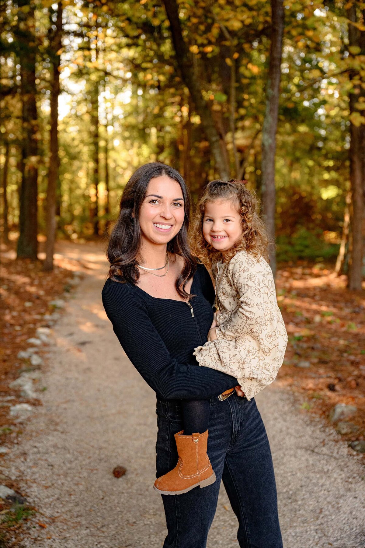 mother dressed in black holds her daughter dressed in cream while standing on a pathway in lancaster, sc