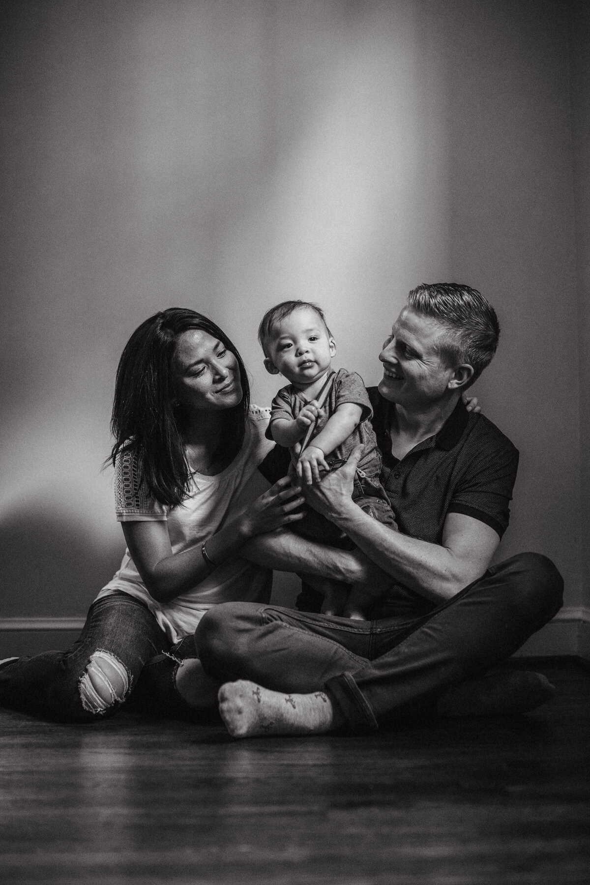 black and white family portrait of parents holding son