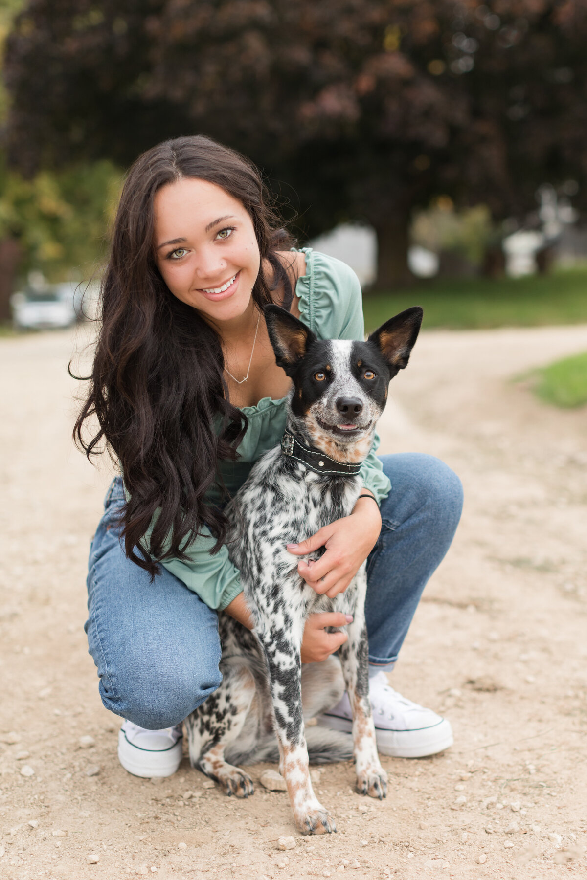 Senior girl crouching down with her dog smiling at the camera