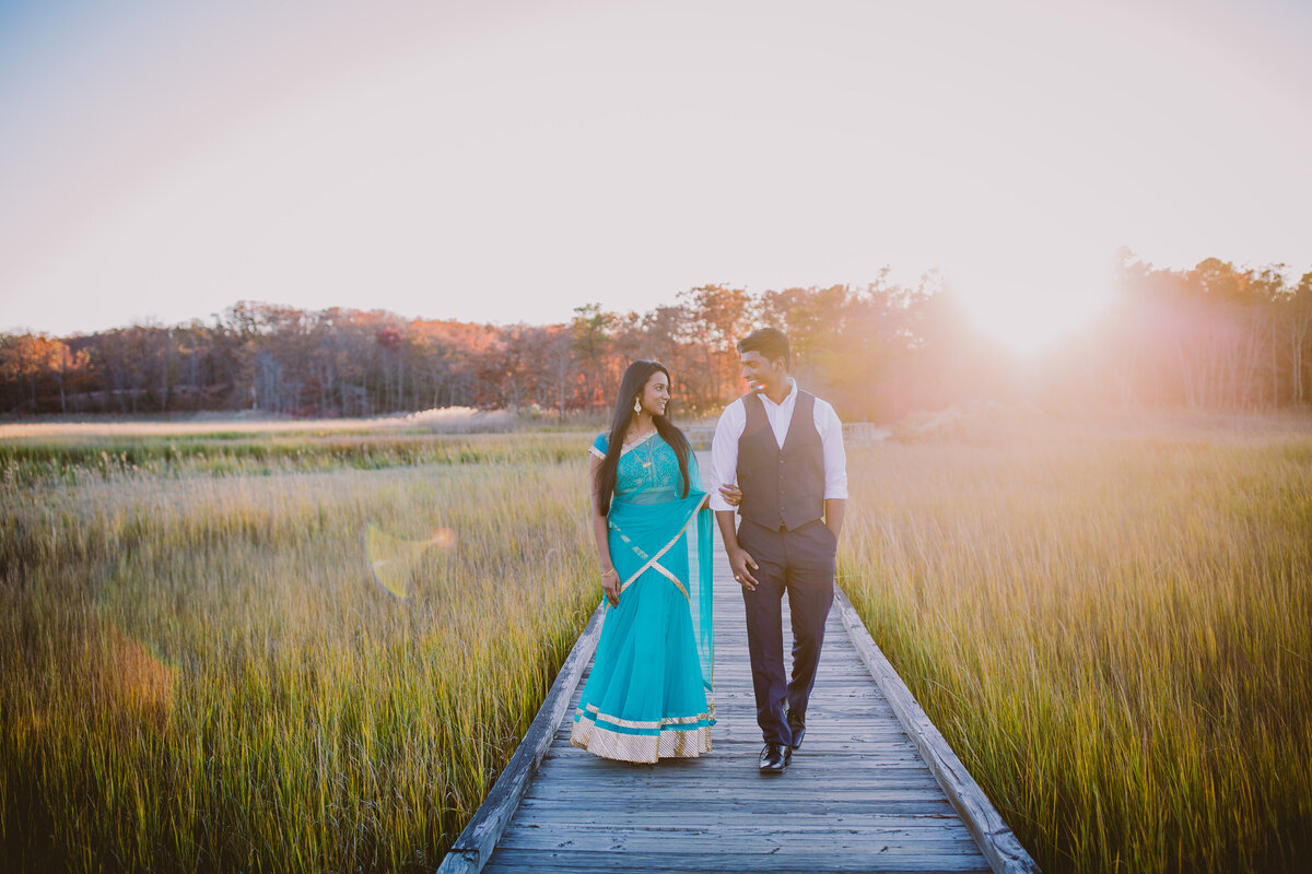 A couple in indian clothes walking through the wooden walkway marsh at cheesequake state park in nj