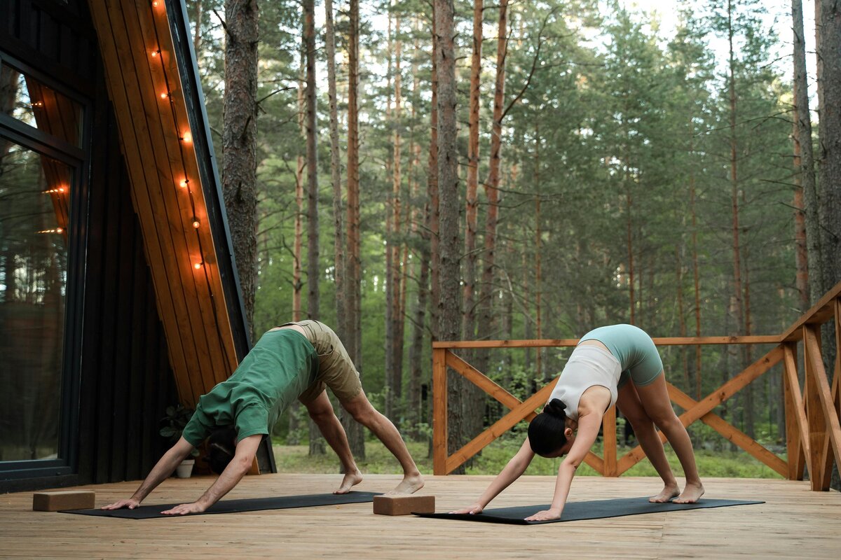 two people doing yoga on the deck of a cabin in the woods