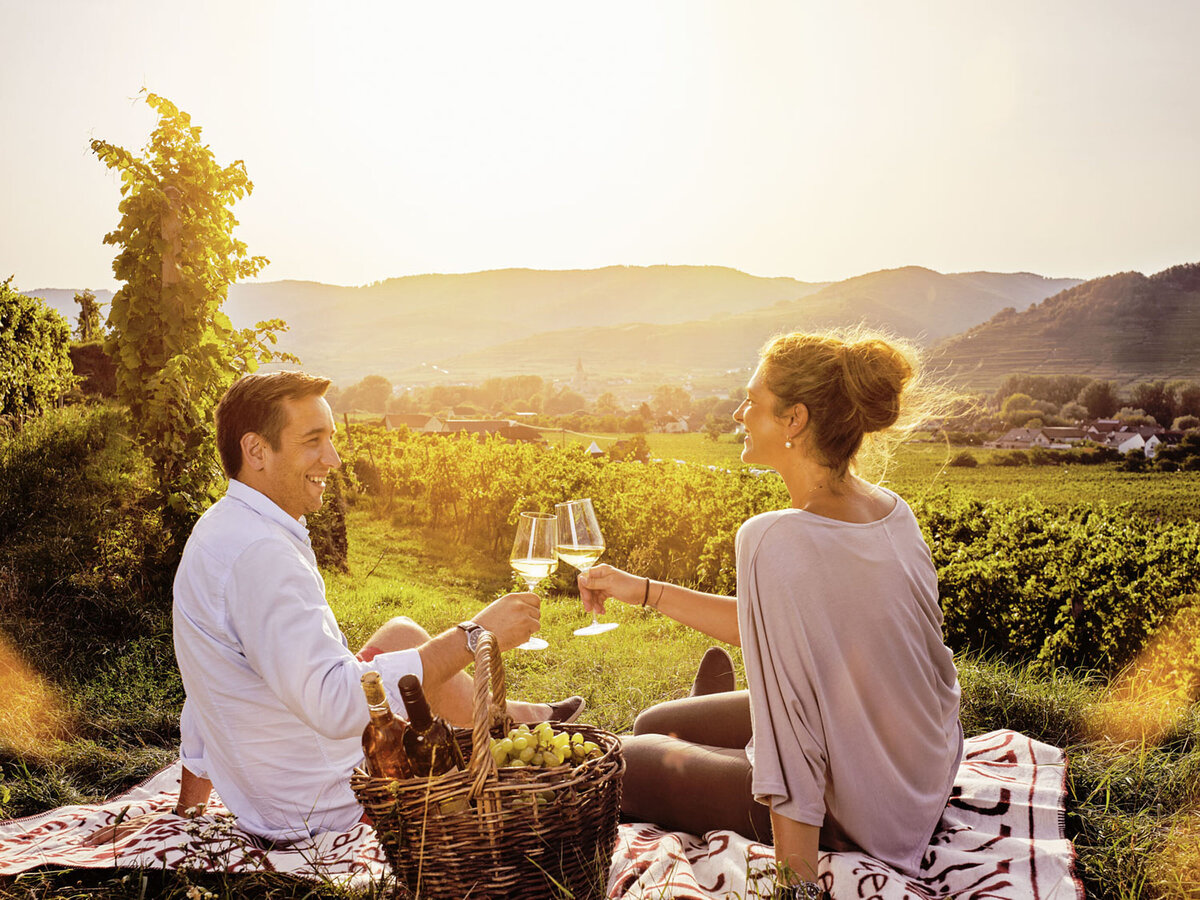 Emotionales Werbefoto eines Paares beim Picknick in den Weinbergen – stimmungsvolle Lifestylefotografie von Atelier Schulte, Werbefotograf in Niederösterreich und Wien.