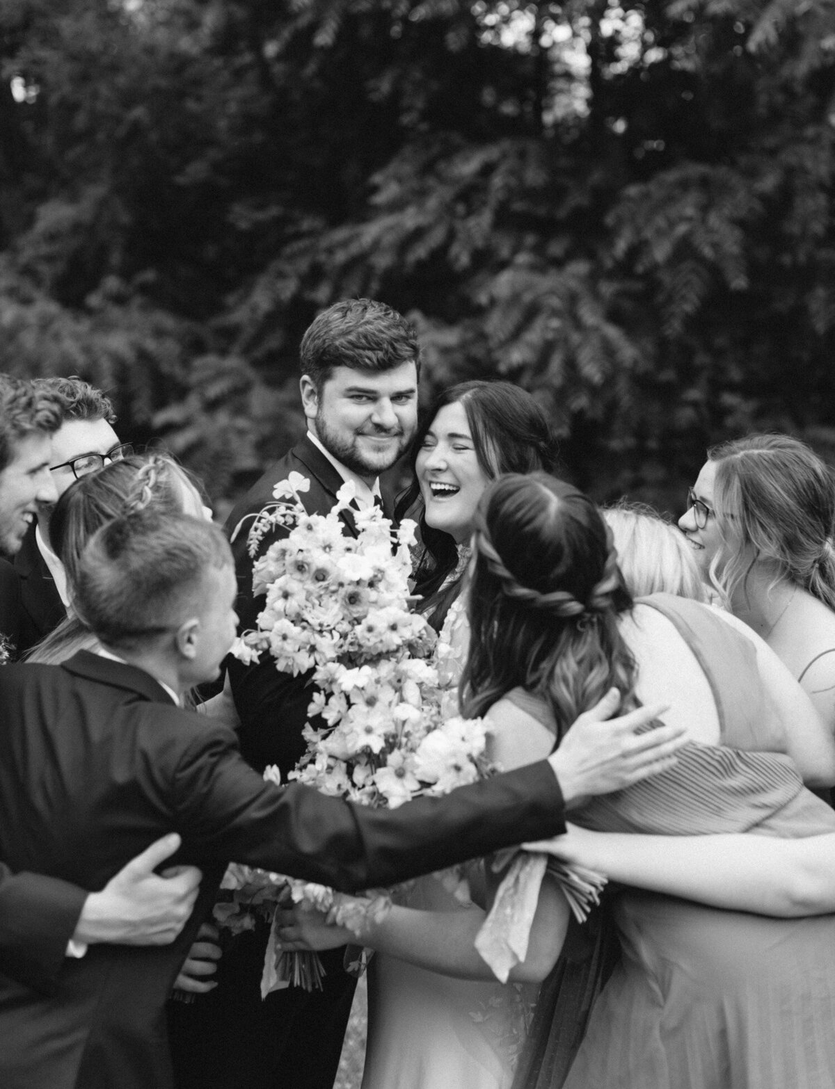 Bride and groom laugh, surrounded by friends at Glass House Community wedding in Grand Rapids