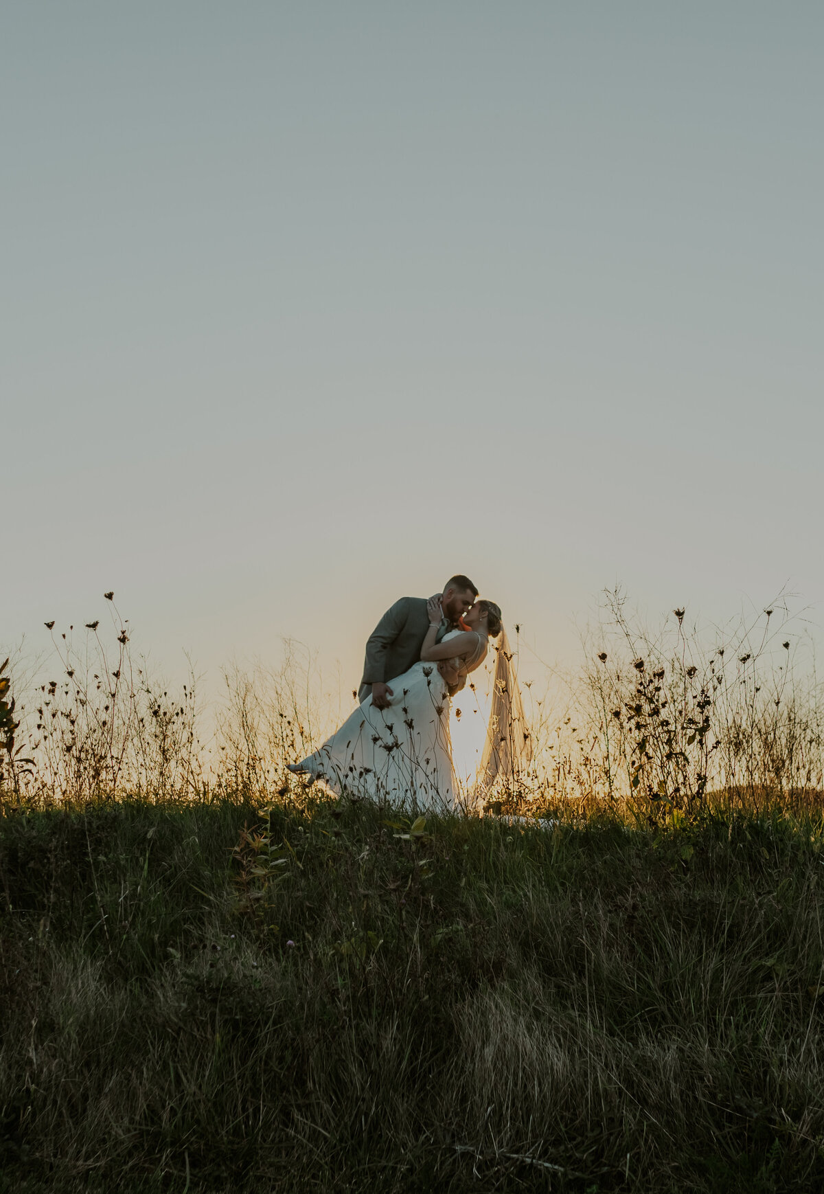 Bride and groom in a sunlit field, rustic Indiana wedding day.