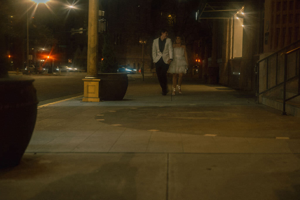 A newlywed couple walking down a city sidewalk.