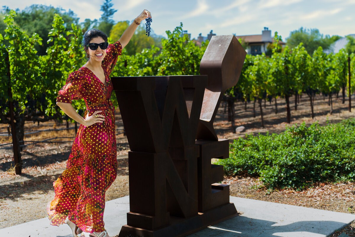 tour guide posing close to vineyard in Napa, holding grapes