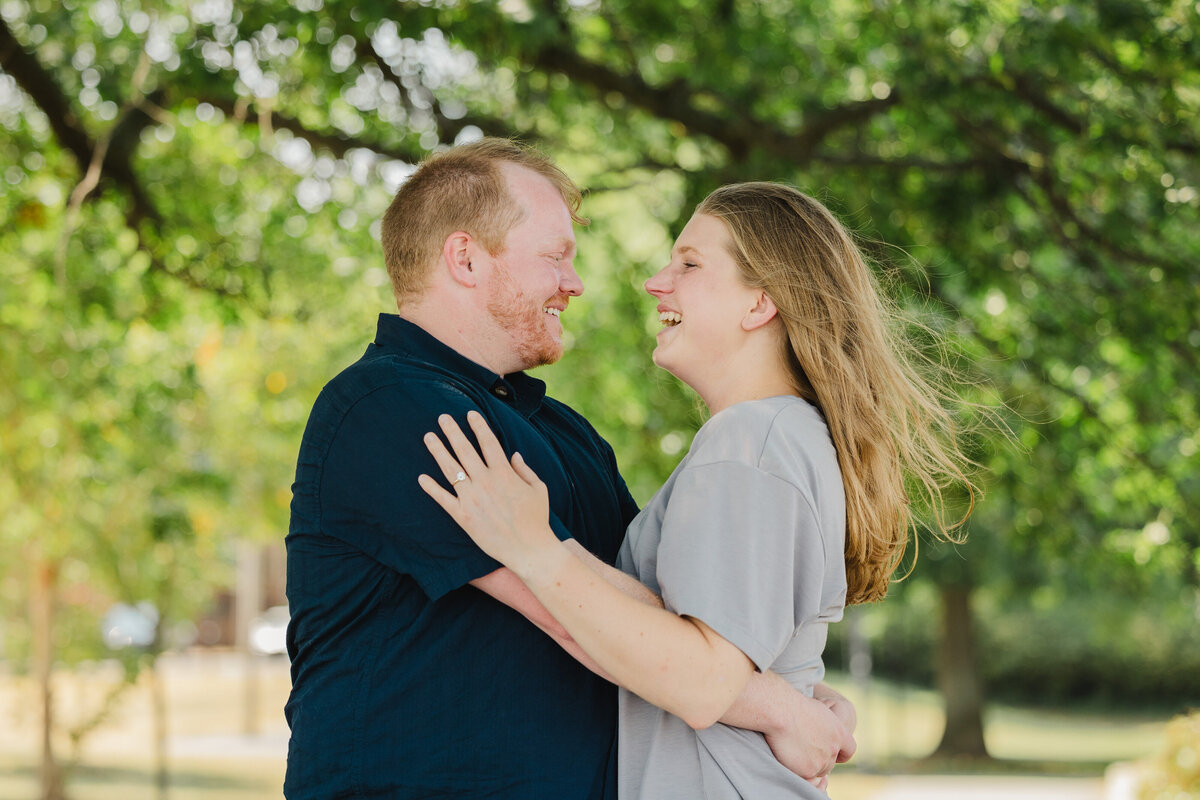 Two people hold one another happily, one of them wearing an engagement ring.