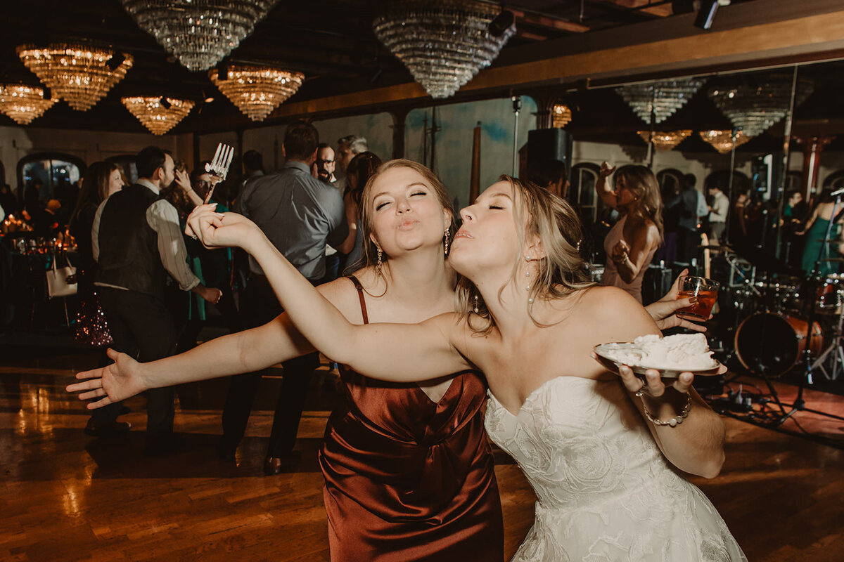 A newlywed dancing and eating cake with a wedding guest 