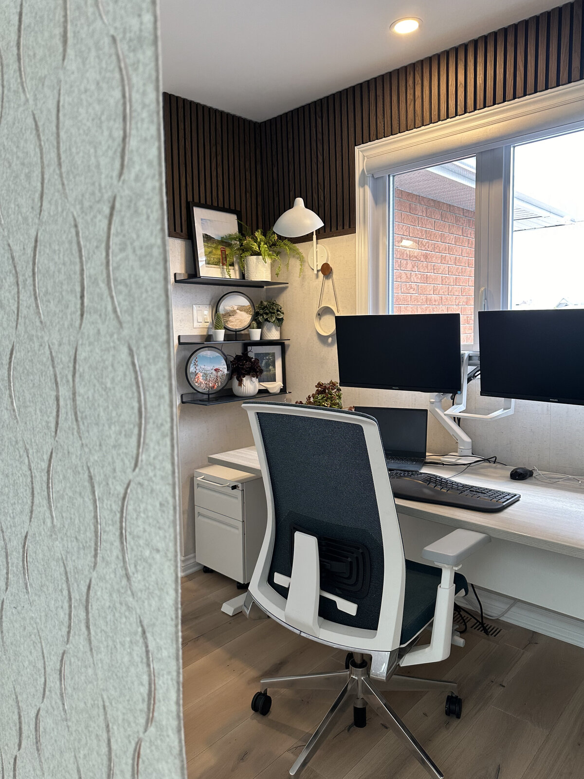 Floating steel wall shelves painted in a deep marine blue complement the custom office fabric, in this modern home office nook design in Barhaven (Ottawa) by Urbanomic Interiors