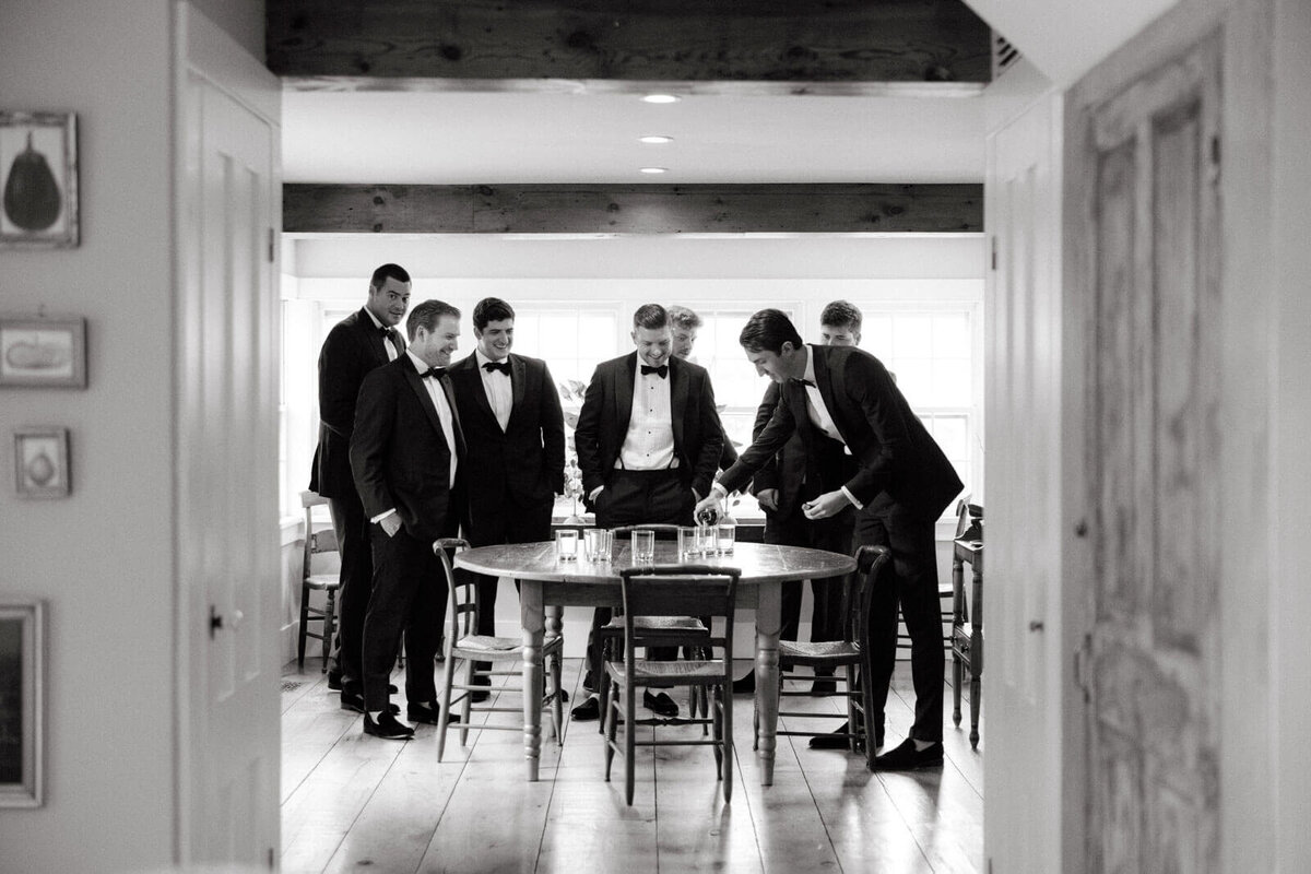 The groom and groomsmen are all smiling and about to drink wine at Lion Rock Farms, CT. Image by Jenny Fu Studio