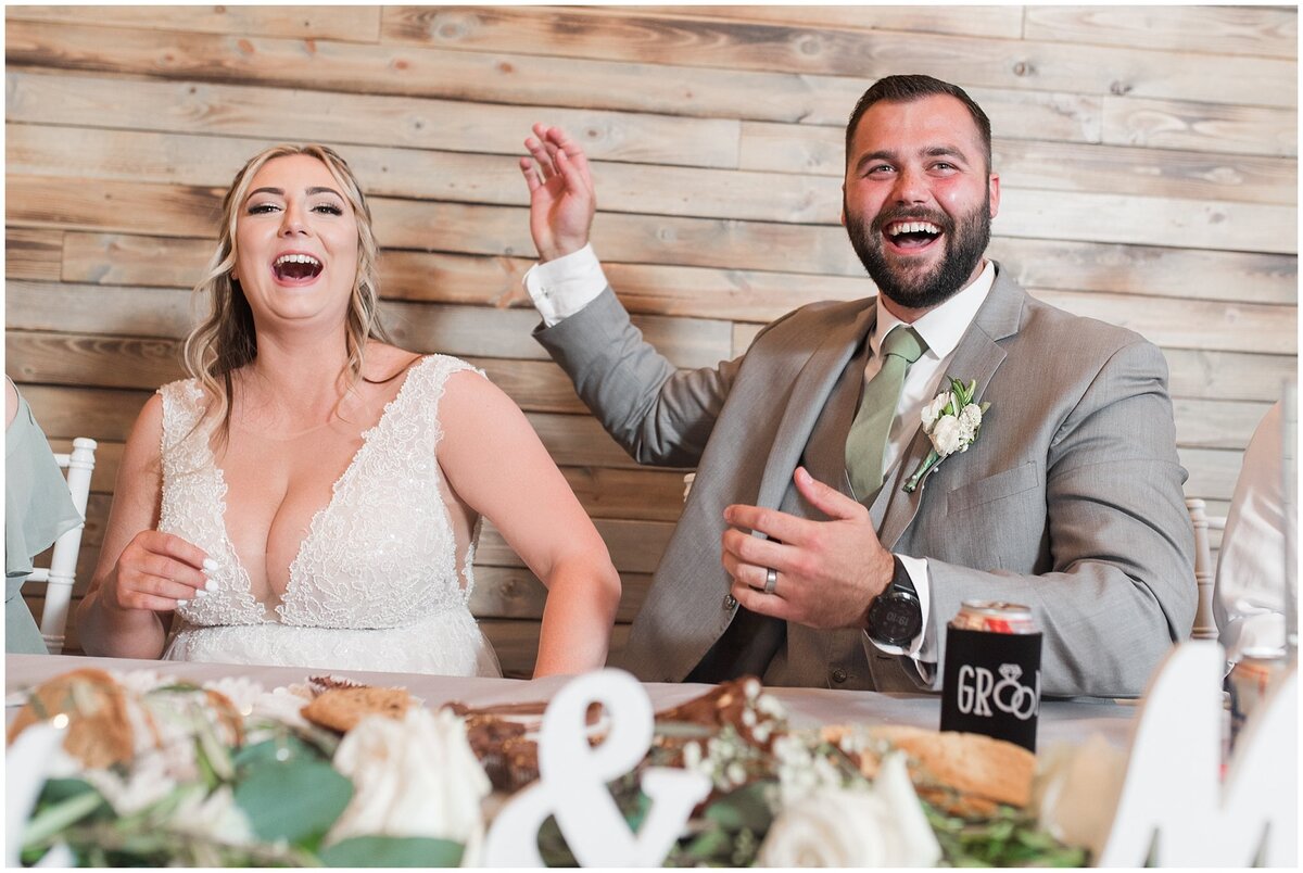 Bride and groom laughing during toasts at Oak Hills Reception and Event Center