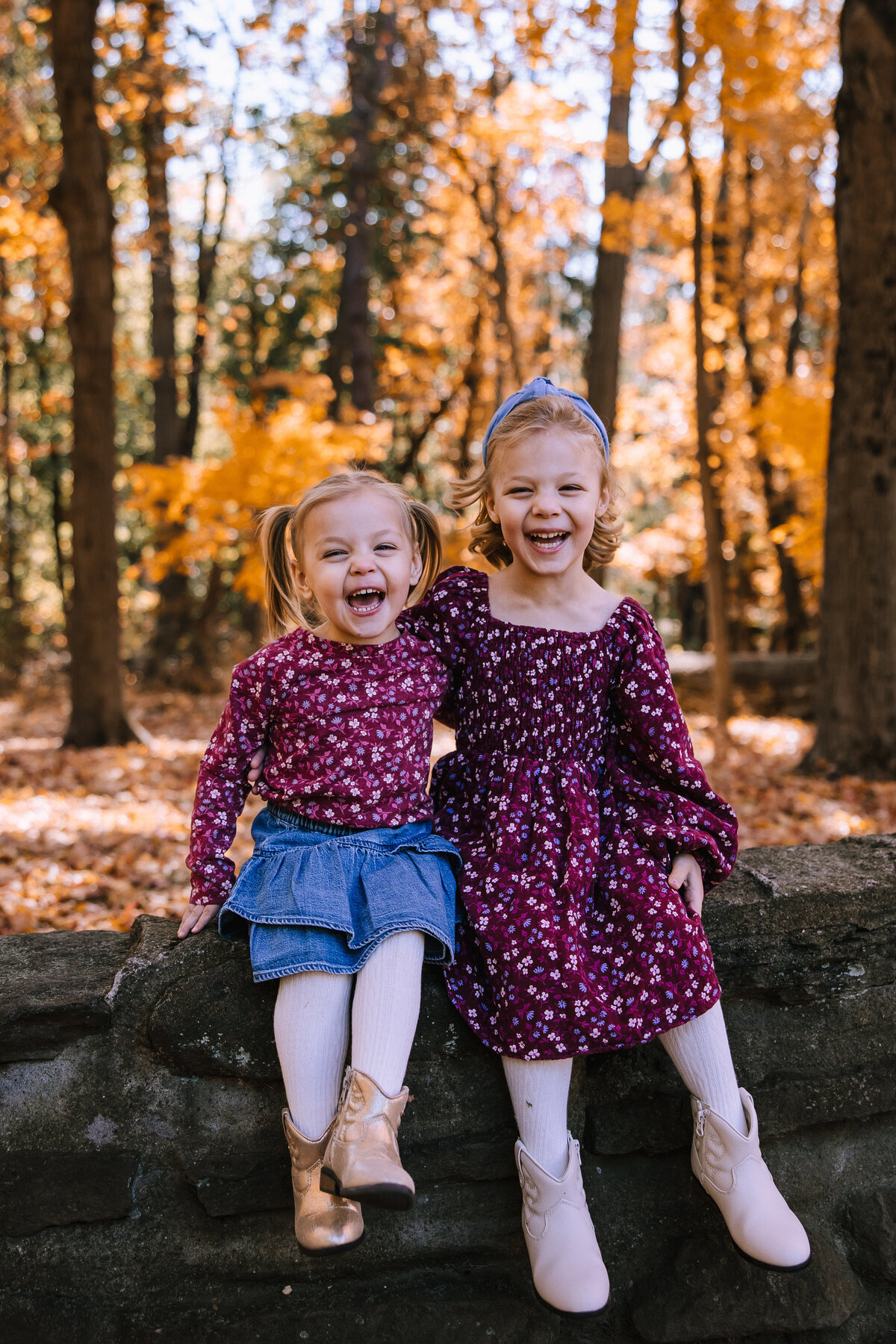 Two sisters sitting on a rock giggling for family photos in Pittsburgh.