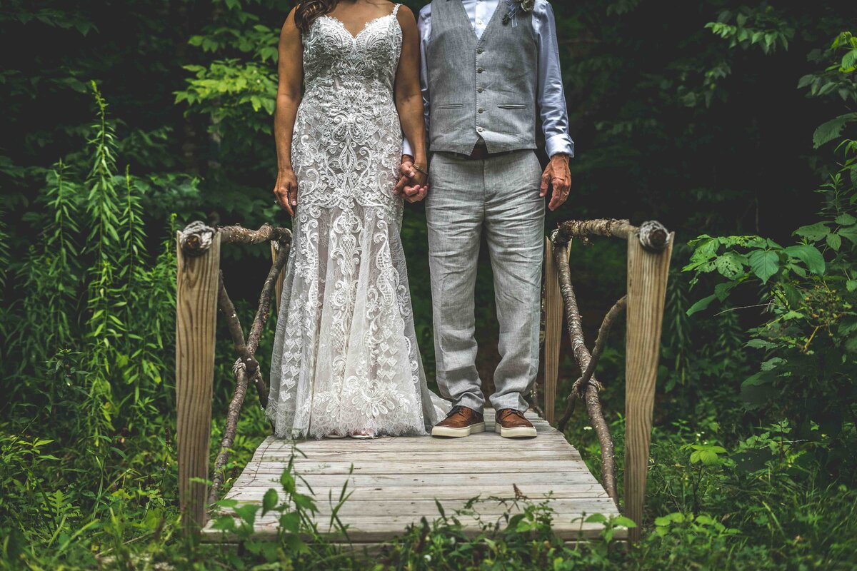 wedding couple holding hands on a bridge in the woods