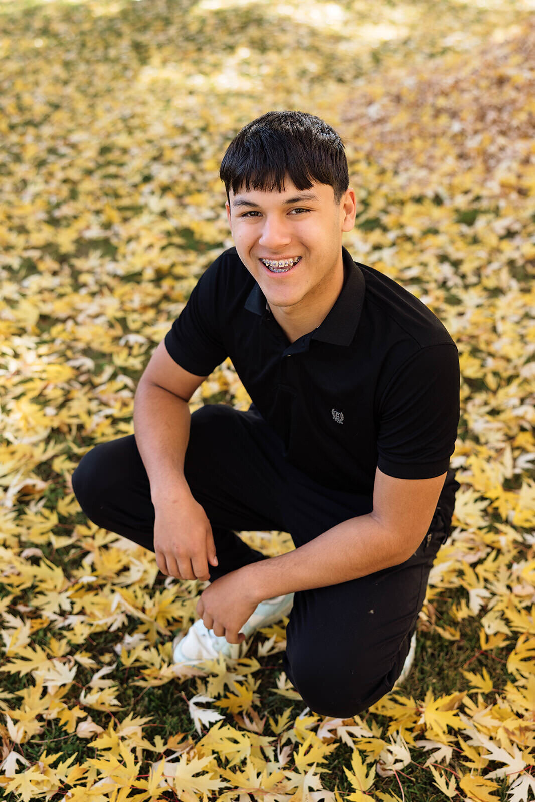 Senior guy crouching in fall leaves