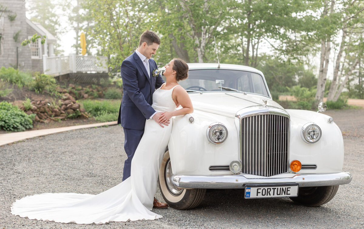 bride and groom posing in front of luxury car at Inn at Bay Fortune