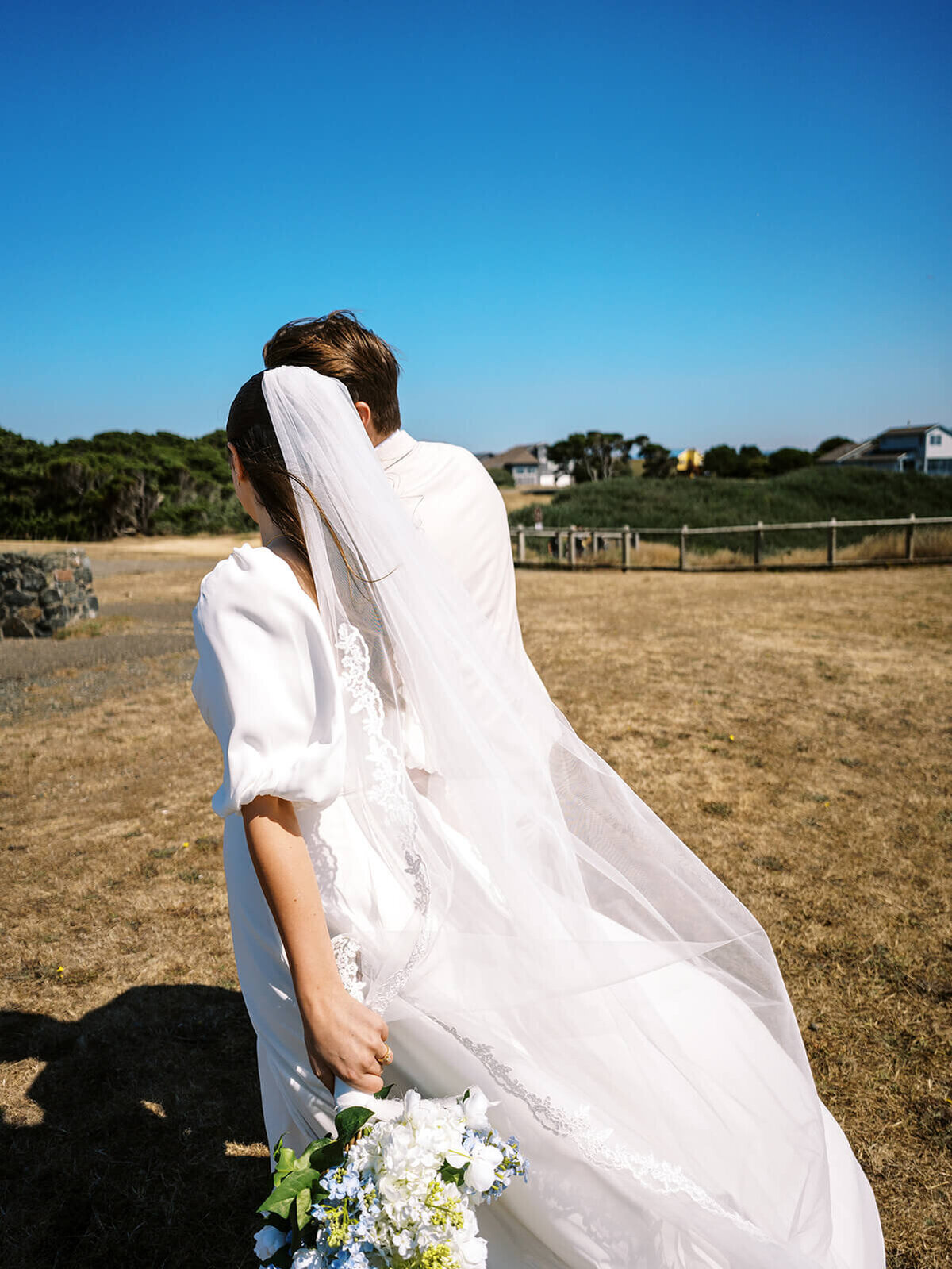 Side view of a bride and groom walking, representing the documentary style photography of Among the Oaks.