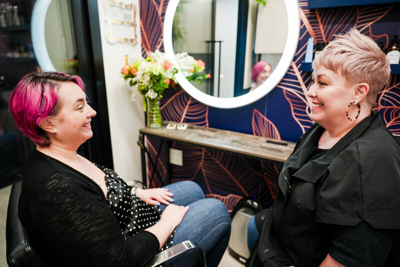 Hairstylist in salon consulting with a client with bright pink hair