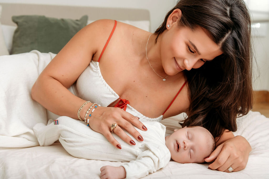 Connecticut newborn photographer captures intimate moment of mother gently touching her sleeping newborn baby in white during lifestyle shoot