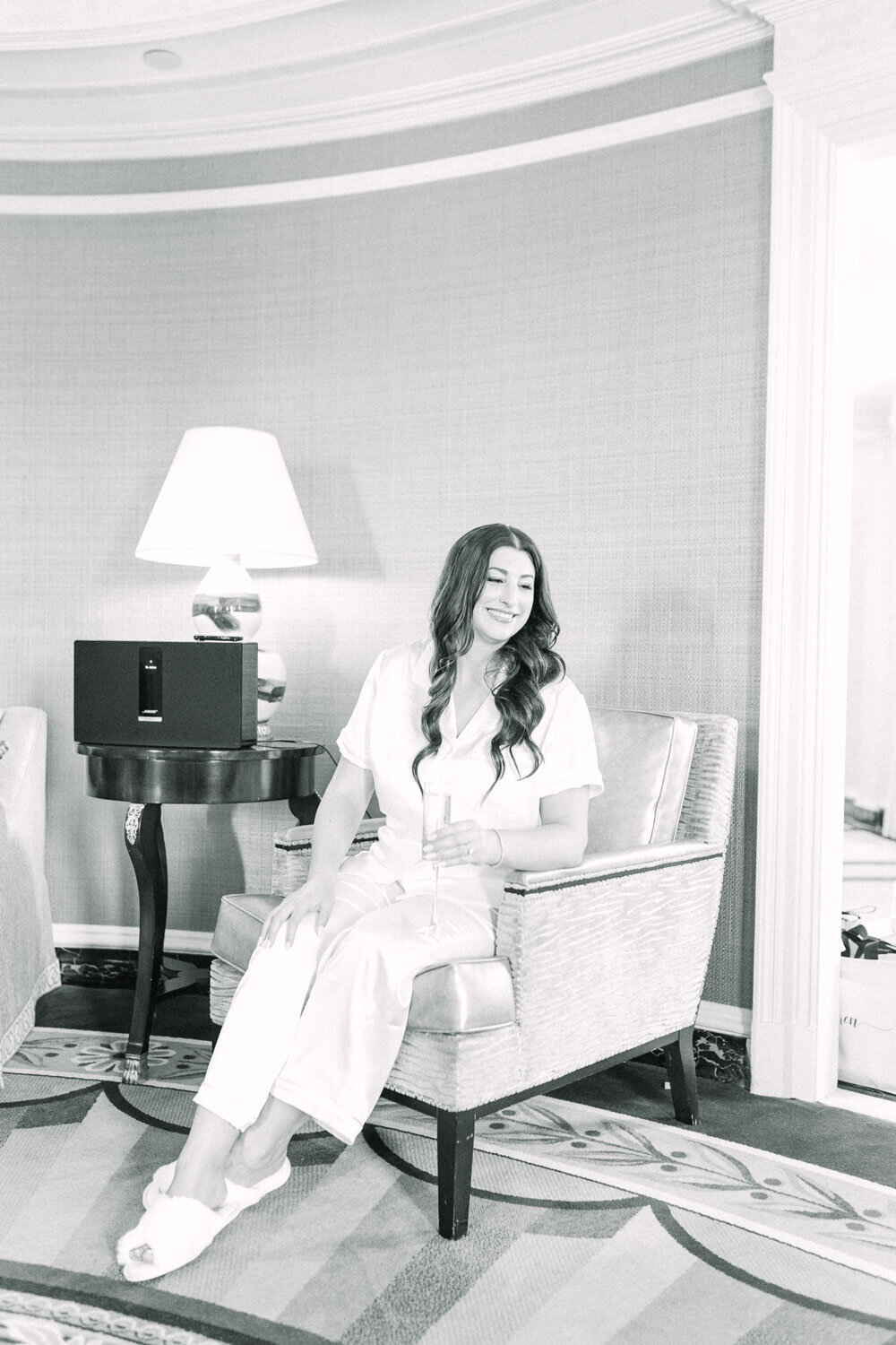 Bride sitting with champagne glass during wedding morning prep