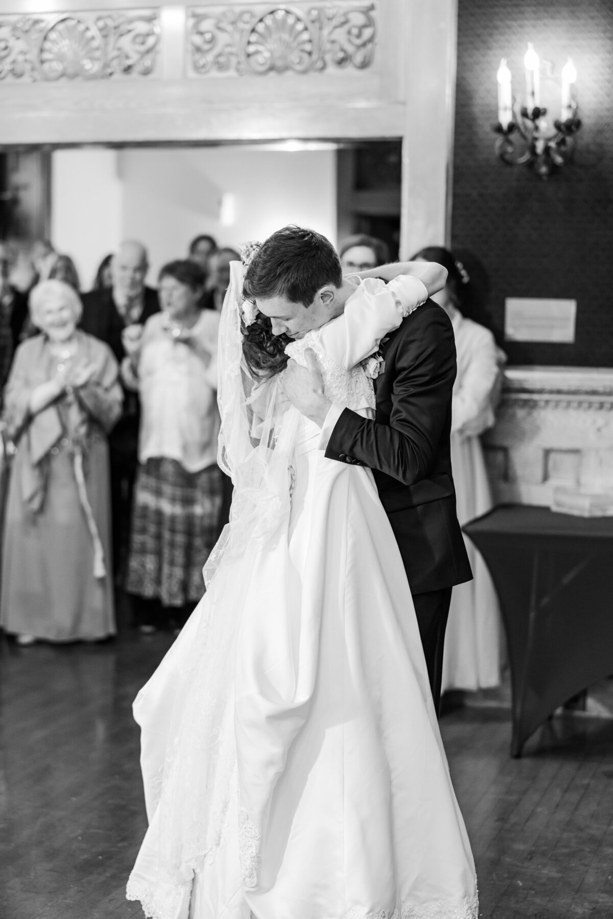 Bride & Groom hugging each other during their first wedding dance in a beautiful indoor wedding venue