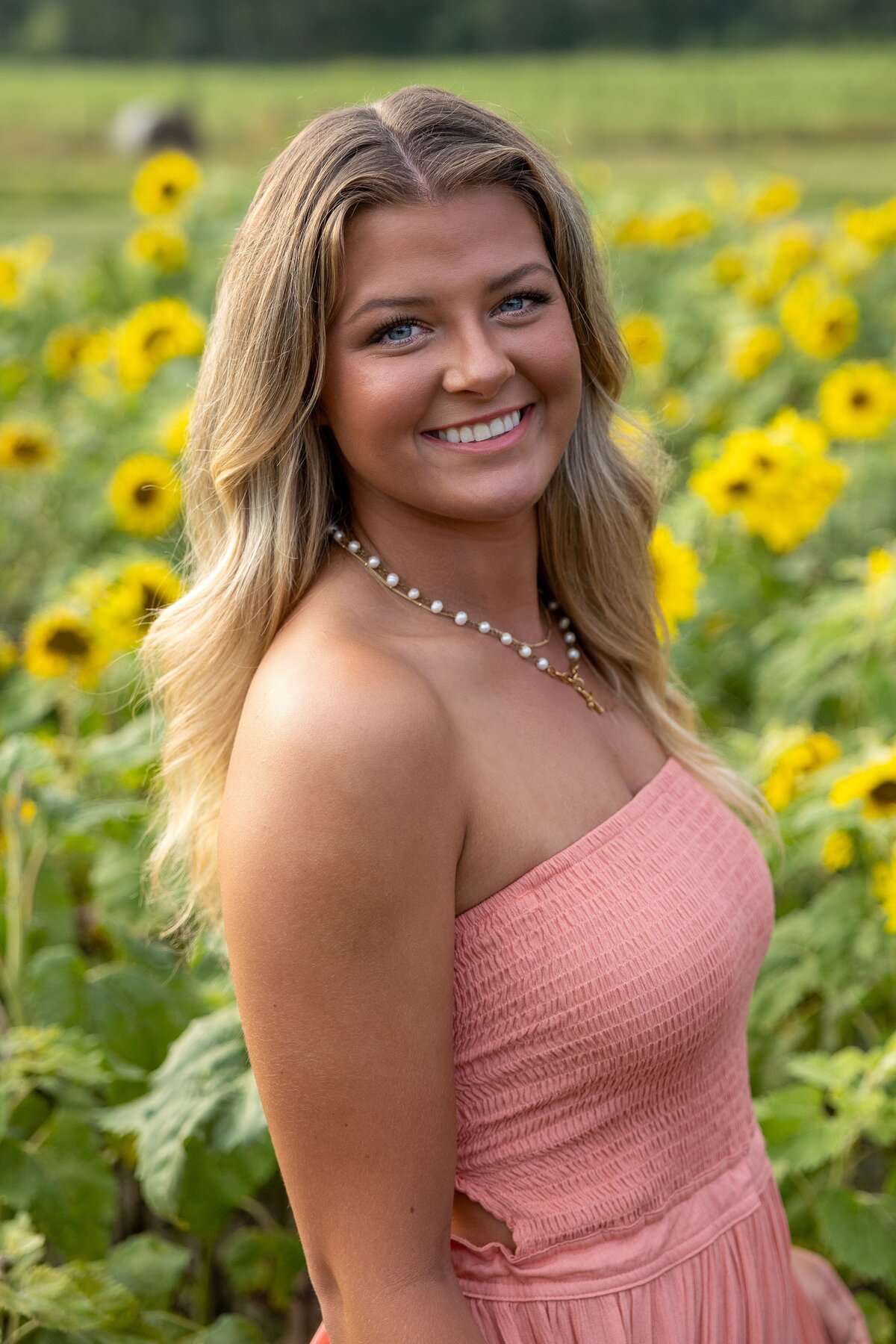 a person smiling in a field of sunflowers