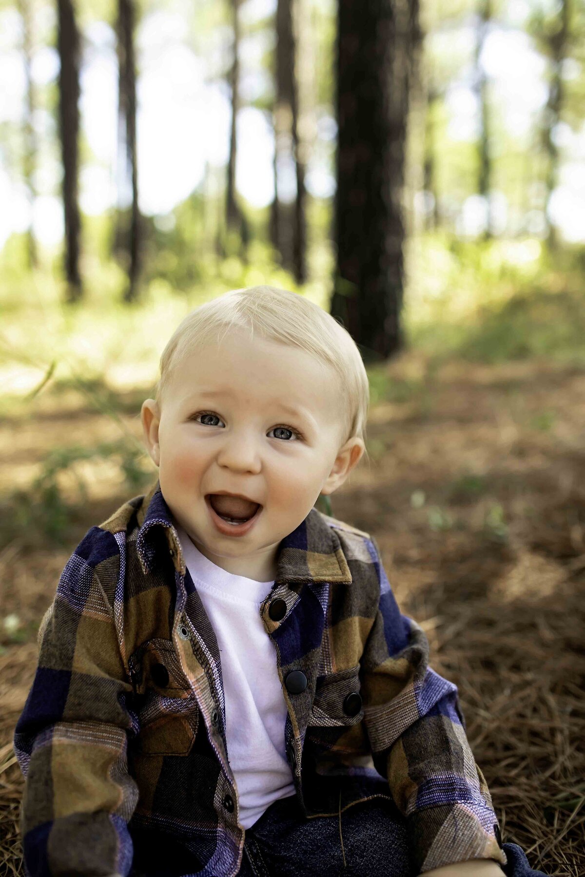Birthday boy in suspenders and overalls, standing in front of towering pine trees with a big grin